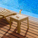 A Lancaster Table & Seating sand side table with a drink on it next to a chair by a pool.