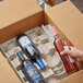 A hand holding a Lavex wine bottle in a cardboard box with dividers.