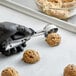 A person in gloves using an OXO Good Grips black squeeze handle disher to scoop cookie dough.