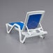 A white Lancaster Table & Seating chaise lounge chair with a blue sling seat.