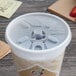 A Dart translucent foam cup with a lid and straw on a table.