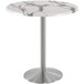 A Holland Bar Stool white marble round bar height table with a stainless steel base.