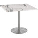 A white marble Holland Bar Stool table with a stainless steel round base.