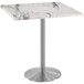 A Holland Bar Stool white marble table with a stainless steel metal base.