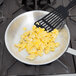 A Vollrath Arkadia aluminum frying pan with scrambled eggs and a spatula.