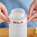 A person holding a plastic bottle with a white silicone label that says "Mild"