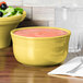 A yellow Fiesta Gusto Bowl filled with pink liquid on a table.