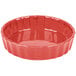 A red fluted china quiche dish with a white background.