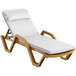 A Lancaster Table & Seating sand resin chaise lounge with white cushion and pillow.