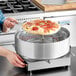 A woman using a VacPak-It pizza film wrapping machine to wrap a pizza.