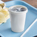 A white plastic cup with a flat lid and straw on a blue tray.