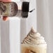 UPOURIA Cookies & Cream shakeable topping being poured onto a coffee drink.