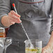 A person using an American Metalcraft stainless steel twisted bar spoon to mix a drink in a glass on a counter.