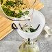 OXO Good Grips 3-Piece Multi-Purpose Plastic Funnel Set being used to pour herbs into a glass container with liquid and leaves in it.