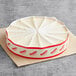 A round white and red container with white strips on top containing two David's Cookies New York Cheesecakes.