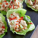 Lettuce cups filled with Hungry Planet plant-based chicken and vegetables on a plate.