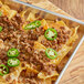A tray of nachos with Beyond Meat Feisty Beef Crumbles and jalapenos on top.