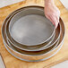 A hand holding a Choice 16" stainless steel sieve.