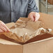 A person opening a box with Lavex natural kraft void fill packing paper.