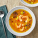 A bowl of soup with shrimp next to a bowl of Goya Aji Amarillo Yellow Hot Pepper Paste.