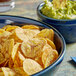 A bowl of Goya Plantain Chips and a bowl of guacamole on a table.