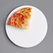 A slice of pizza on a white 6" corrugated pizza circle.