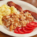 A plate of food with bacon, eggs, tomatoes, and Idahoan Shreds Fresh Cut Hash Browns on a table.