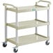 A beige plastic utility cart with three shelves on wheels and handles.