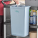 A woman uses a gray Choice refuse bin in a kitchen cart.