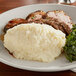 A plate of Idahoan Smartmash Classic mashed potatoes with greens on a table.