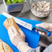 A person cutting bread with a Mercer Culinary blue bread knife.