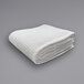 A folded white Oxford Jaipur Thermal Honeycomb hotel blanket on a gray surface.