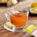 A glass cup of Bigelow I Love Lemon tea with a tea bag on a saucer.