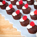 A white GET triangle display tray with chocolate cupcakes topped with raspberries.