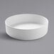 A white Cal-Mil stackable melamine bowl on a gray surface.