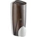 A white plastic Dial hand soap dispenser with brown accents containing brown liquid.