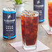A can of La Colombe Brazilian cold brew coffee next to a glass of liquid with ice.