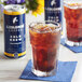 A glass of cold brew coffee with ice next to a blue can of La Colombe Colombian Cold Brew Coffee.