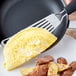 An OXO spatula lifting an omelette from a pan.