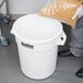 A person pouring rice into a Continental Huskee white ingredient storage bin.