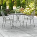 A Lancaster Table & Seating rectangular outdoor table with gray tablecloth and 2 arm chairs on a patio.