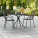 A Lancaster Table & Seating Harbor black table with 2 arm chairs on an outdoor patio.