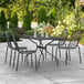 A black Lancaster Table & Seating rectangular outdoor table with modern black chairs on a patio.