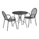 A Lancaster Table & Seating Harbor black metal outdoor bistro set with ornate legs on a table with two chairs.