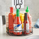 A black wrought iron half round condiment caddy with a number card holder holding a bottle of hot sauce.