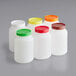 A group of white plastic containers with assorted color lids.
