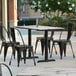 A Lancaster Table & Seating rectangular dining table with smooth finish and outdoor base plates on a patio.