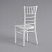 A white Lancaster Table & Seating Chiavari chair with a wooden seat and back.