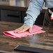 A person using a red WypAll wiper to clean a countertop.
