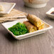 A rectangular white melamine plate with food on it.
